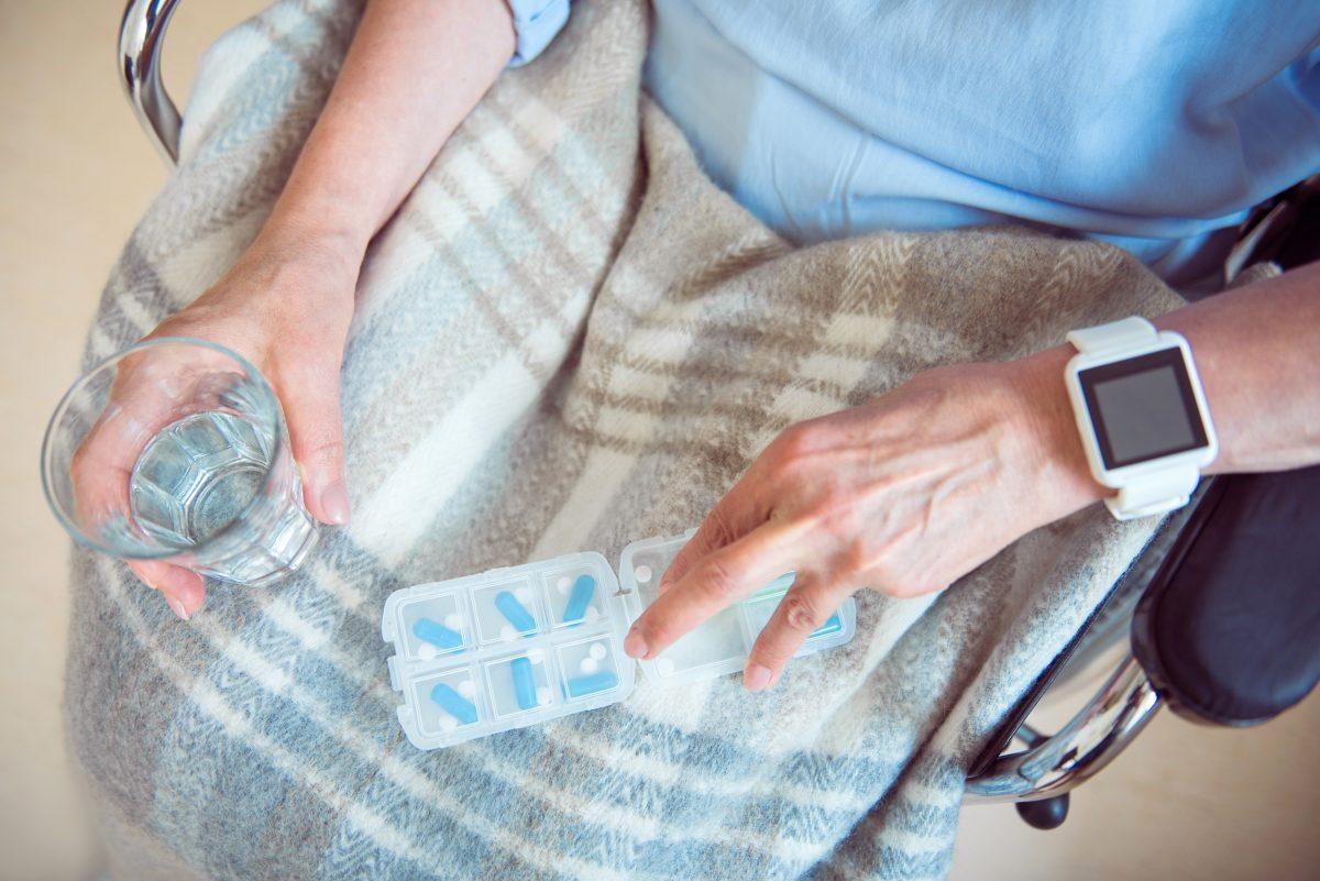 Senior in chair taking medicine